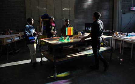 A group of people around a shop table, discussing artwork