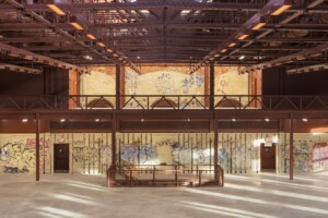 Photo credit: Albert Vecerka/Esto A large two-story room with graffiti on the walls, a steel mezzanine, and a stairway leading down