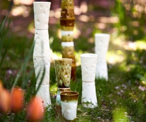 Ceramic sculptures resembling stacked coffee cups in a garden