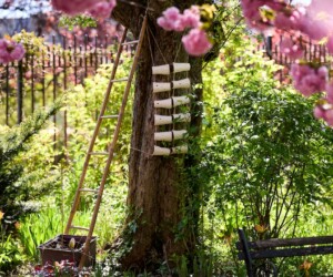 Ceramic sculptures resembling stacked coffee cups hung from a tree