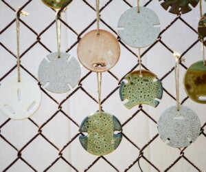 Ceramic artworks resembling coffee cup lids hung on a fence