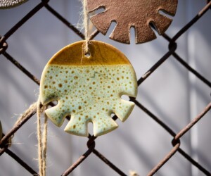 Ceramic artworks resembling coffee cup lids hung on a fence